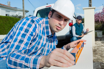 worker checking level of low wall with spirit level