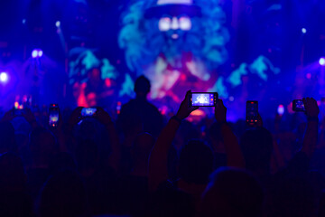 Hands holding phone and making photos on the concert.
