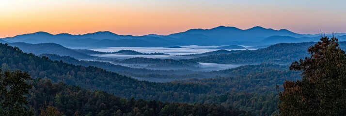Naklejka premium At sunset, a mountain range is framed by low-lying clouds, with trees lining the foreground