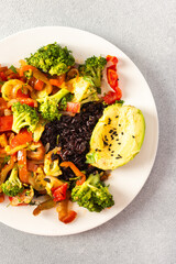 A hearty and nutritious breakfast of black rice with stewed vegetables like tomatoes, zucchini,...