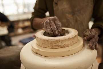 African ceramist molding clay on a pottery wheel in a studio