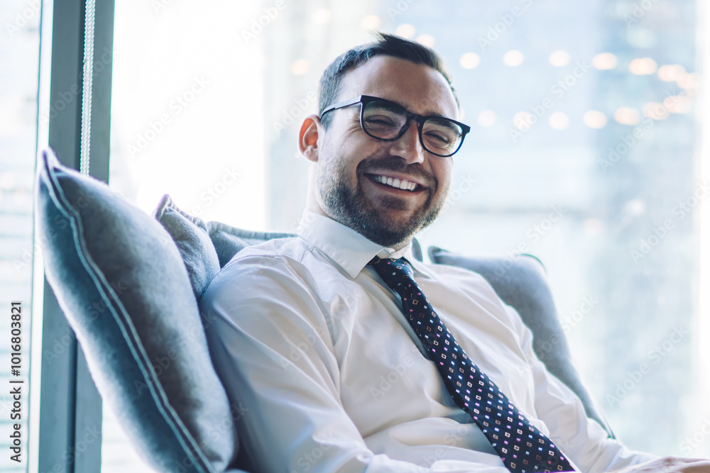 Aufkleber portrait of successful cheerful male trader resting in comfortable chair and smiling at camera durin