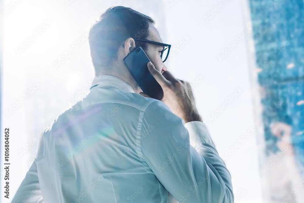 Aufkleber back view of male entrepreneur talking with colleague via mobile phone during working day in enterpr