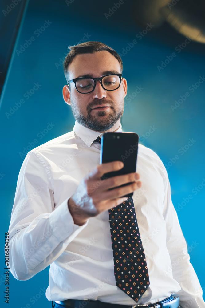 Aufkleber below view of handsome young entrepreneur dressed in white formal shirt and tie sending sms message 