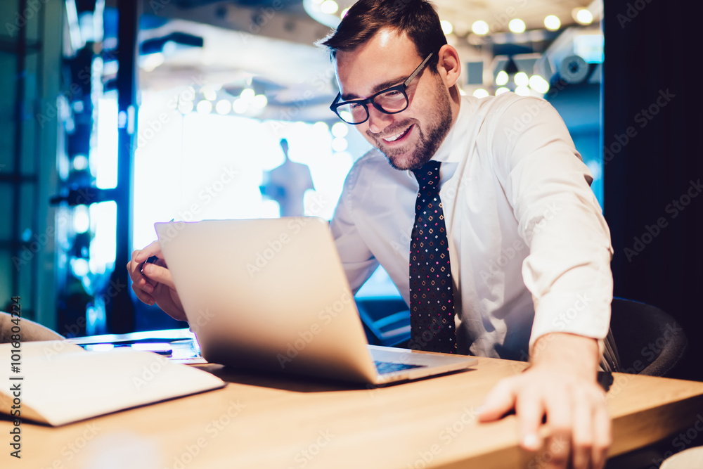 Poster happy businessman sitting at office desk looking at computer screen browsing website and smiling usi