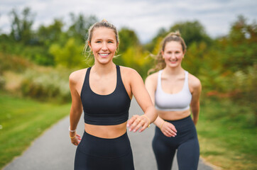 Fototapeta premium Healthy two sporty young girls jogging and stretching outdoors