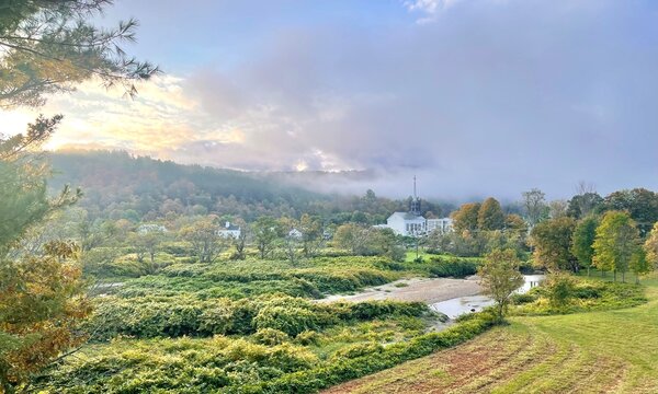 Early morning panorama landscape scene of small town Vermont with a church, fall colors, and dramatic clouds