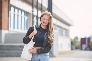 Fototapeta premium Young girl high school or college student She is on her way to class near university building