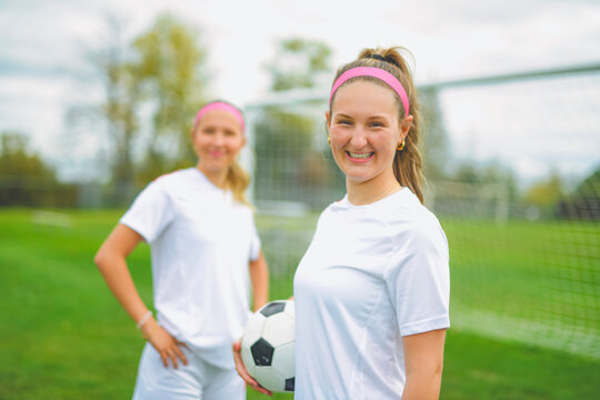 two soccer player friends with a football in a sport uniform wearing in white