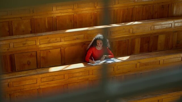 Distant view Caucasian girl student Hispanic woman Latina American female in university college auditorium high school academy writing task homework test exam write in classroom study education learn