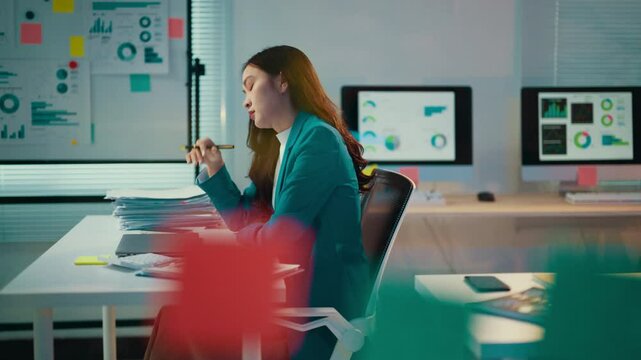 Asian accountant is working late on a laptop. She is getting increasingly stressed as the evening progresses and is eventually overwhelmed by her work