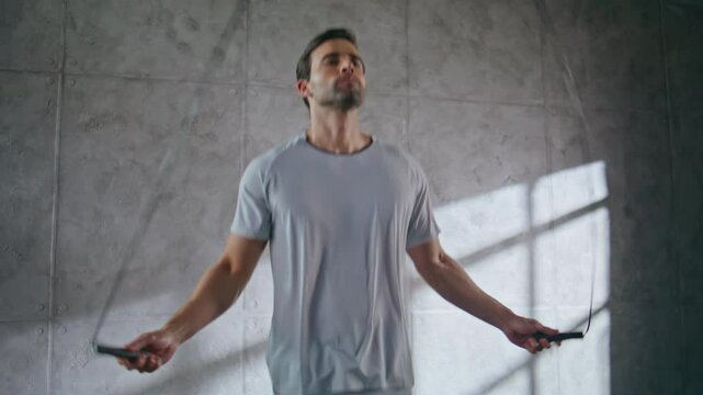 Closeup fitness man jumping in loft sport club. Athlete using skipping rope