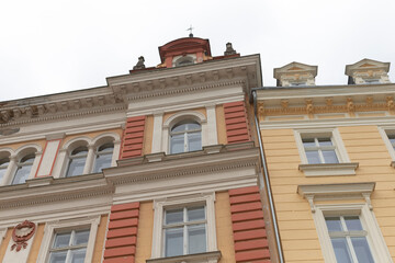 A yellow building that features a striking red roof is situated right next to another building, creating a unique streetscape