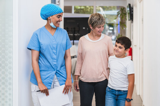 Dental hygienist accompanying mother and child to the consultation room for treatment