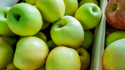 A pile of fresh, ripe green apples in a wooden crate, symbolizing healthy eating or the harvest season