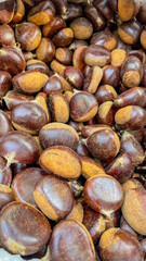 A pile of fresh, glossy chestnuts perfect for roasting during autumn holidays, symbolizing tradition and warmth