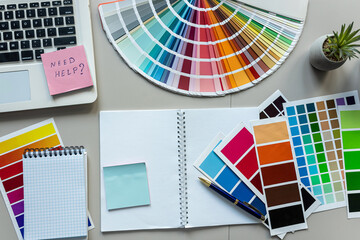 Office desk table with colour swatches book computer laptop, empty notepad pen