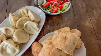 A rustic Eastern European meal featuring dumplings, fresh salad, and bread, perfect for celebrating traditional holidays and gatherings