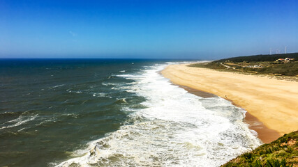 A picturesque and sunny beach with waves crashing along a vast coastline, ideal for summer...