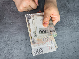 woman holds Polish money and counts 100 200 zl pln zloty banknotes, salary for payment