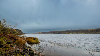 Tranquil autumn lake scene with cloudy skies and foliage, capturing the essence of solitude and reflection in nature