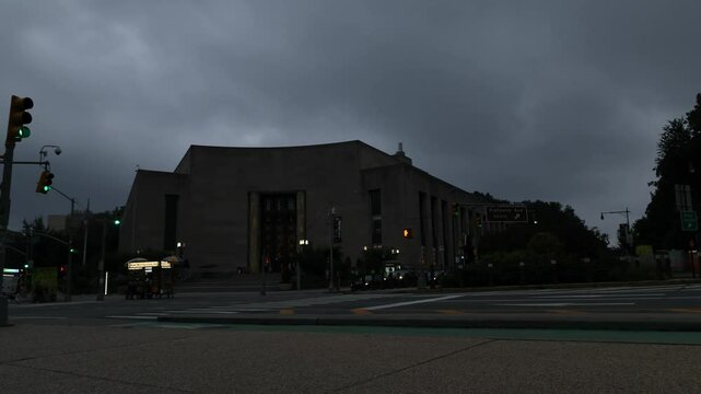time lapse of cyclists and cars moving through flatbush avenue in the evening (brooklyn public library nyc new york city) stormy gray sky weather rain fast moving clouds