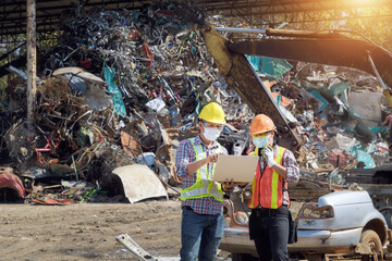 Two workers looking at a laptop in a recycling centre, Thailand