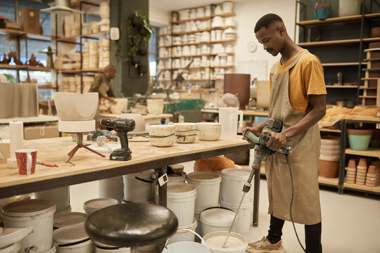 African potter using a mixer in a large ceramics studio - Powered by Adobe