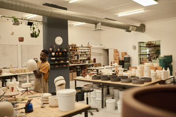 Young African ceramist working on a pot at a studio bench