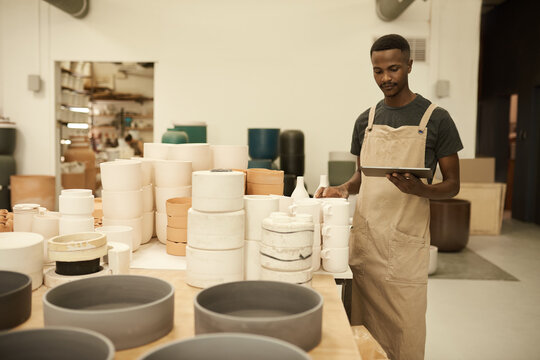 African potter doing inventory using a tablet in a ceramics workshop