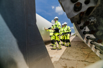 engineers in high visibility safety gear conduct a detailed inspection of a wind turbine blade at a...