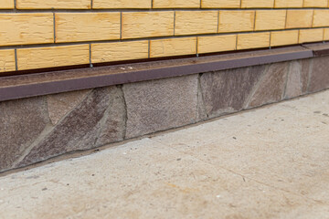 The basement of the brick house is lined with stone. Facing with natural stone