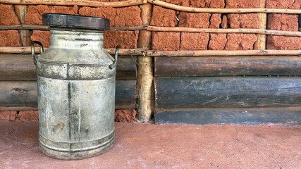Old iron container for transporting fresh milk on a rustic background.