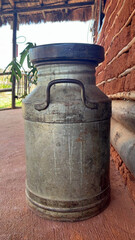 Old iron container for transporting fresh milk on a rustic background.