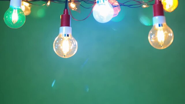 Colorful isolated string lights hang against green screen chroma key background. Warm glow of bulbs creates festive ambiance. Each light shines. Holiday new year celebration. Joy Christmas. Chromakey.