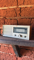 Old radio on a wooden shelf on a rustic wall.