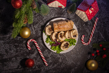 Flat lay appetizer of turkey or chicken meat with nuts and prunes on a black textured background with Christmas tree branches, Christmas balls and candy canes. serving for a Christmas party or New