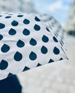 Close-up of a person holding an open umbrella with raindrop pattern