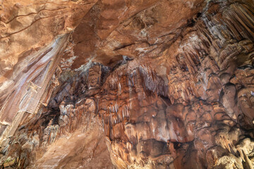 A cave with a brown and white color scheme. The cave is filled with various formations, including stalactites and stalagmites. Scene is one of awe and wonder.