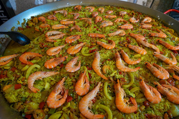 A vibrant seafood paella at a food festival, brimming with shrimp, calamari, and clams. The dish is colorful, with fresh ingredients.