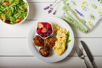 Turkey burgers with scrambled eggs and berries. View from above