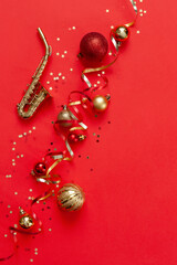 Festive red Christmas and New Year background with Miniature golden saxophone copy and Christmas decor. Top view, copy space, flat lay.