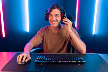 Host channel of gaming smart streamer playing online game to be winner, wearing headphone with viewers live steaming on media social online for selected team competition at neon light room. Pecuniary.