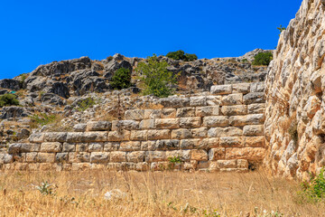A wall made of stone blocks is seen in the distance. Ruins of the ancient city of Philippi, Greece