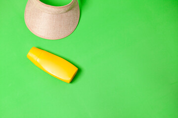 Jar of yellow sunscreen and visor on green background. mockup. Summer concept. Sun protection concept. copy space.