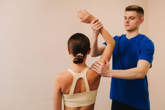 Doctor is doing osteopathy therapy to heal from back muscle conditions. Woman is having shoulder physiotherapy to reduce pain and increase range of motions.