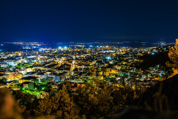 A city at night with lights on the buildings and trees