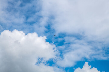 the plane is flying in the sky, beautiful white cumulus clouds in blue sky, natural background, wallpaper