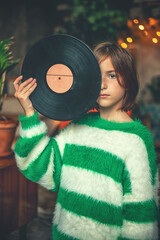 Cute teen girl holding a retro vinyl record in front of her face, with copy space for text