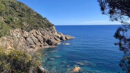 Fototapeta premium Serene coastal view of rocky cliffs meeting crystal-clear waters in a sunny landscape